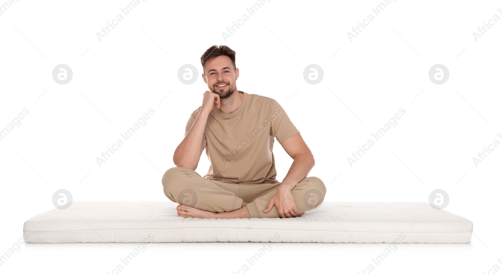 Photo of Smiling man sitting on soft mattress against white background