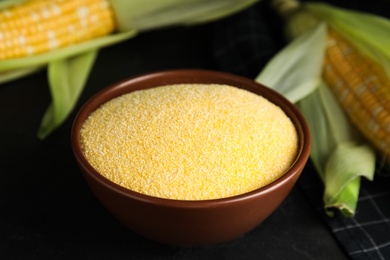 Photo of Cornmeal in bowl and fresh cobs on black table