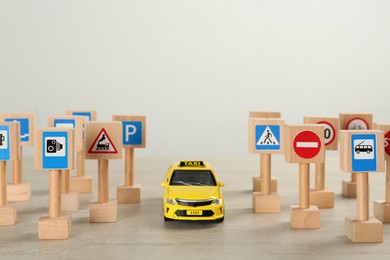 Photo of Many different miniature road signs and car on wooden table, space for text. Driving school