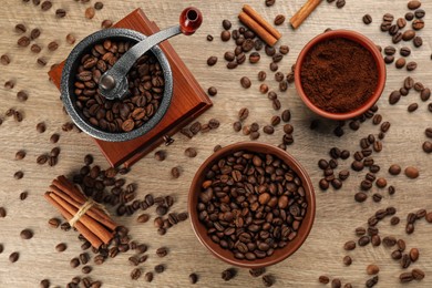 Vintage manual coffee grinder with beans, powder and cinnamon on wooden table, flat lay