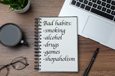 Image of Notebook with list of bad habits on wooden table, flat lay