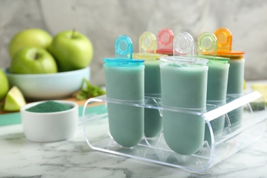 Photo of Spirulina popsicles in ice cream mold on marble table