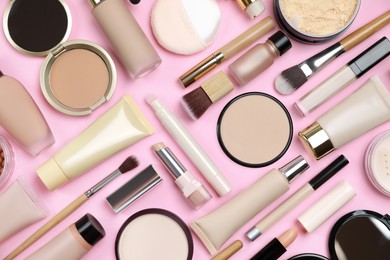 Photo of Face powders and other decorative cosmetic products on pink background, flat lay
