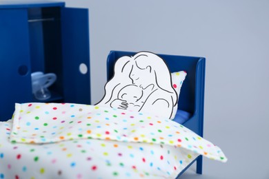 Photo of Maternity leave concept. Baby pacifier, paper cutout of mother and child in toy room