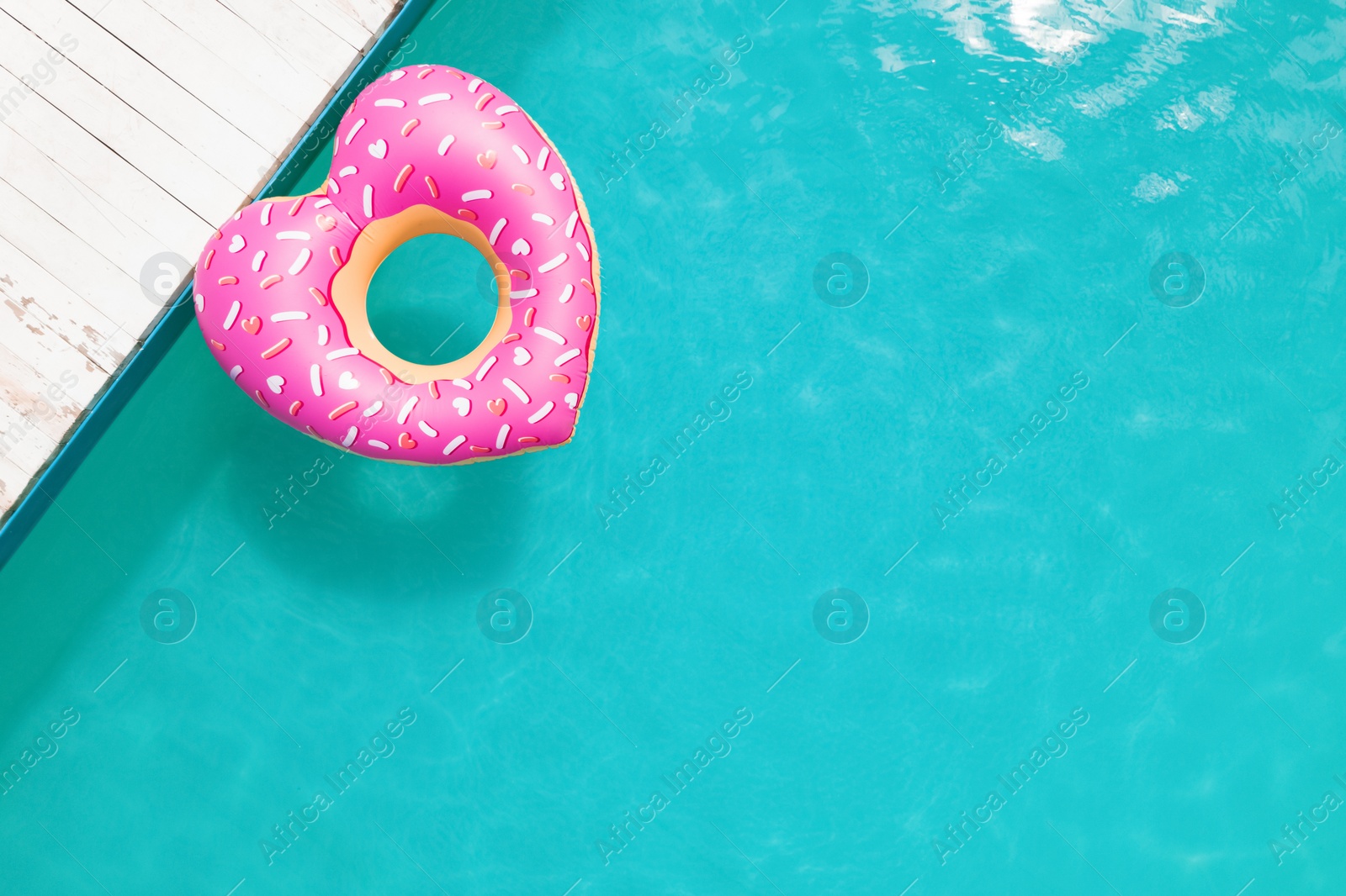 Image of Top view of inflatable ring floating in swimming pool, space for text. Summer vacation