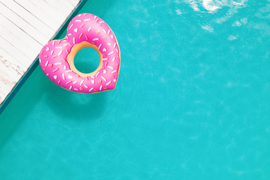 Top view of inflatable ring floating in swimming pool, space for text. Summer vacation