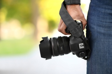 Photographer with professional camera outdoors, closeup view