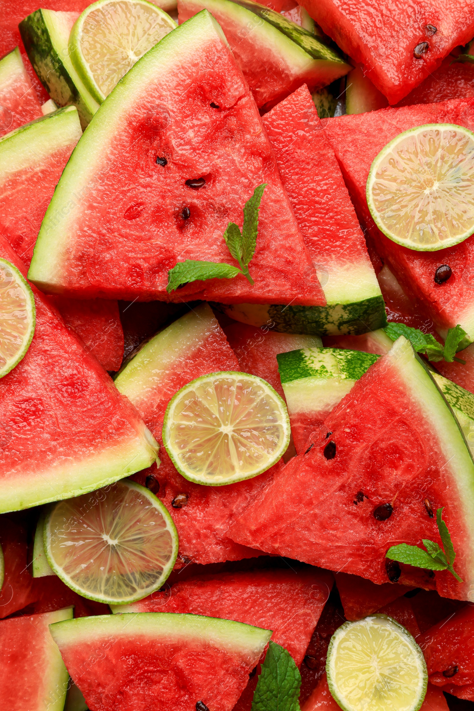 Photo of Slices of juicy watermelon with lime and mint as background, top view