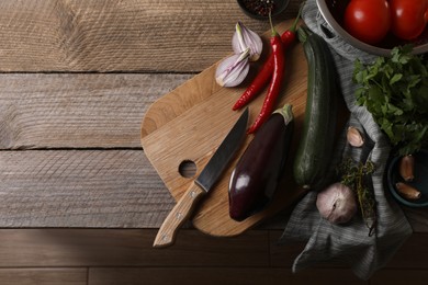Cooking ratatouille. Vegetables, herbs and knife on wooden table, flat lay with space for text