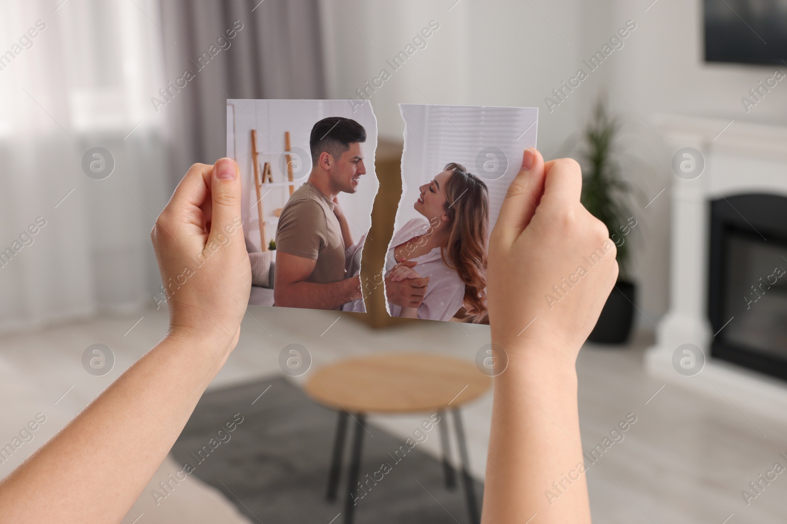 Photo of Woman holding torn photo in room, closeup. Divorce concept