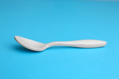 Photo of New clean empty spoon on blue background