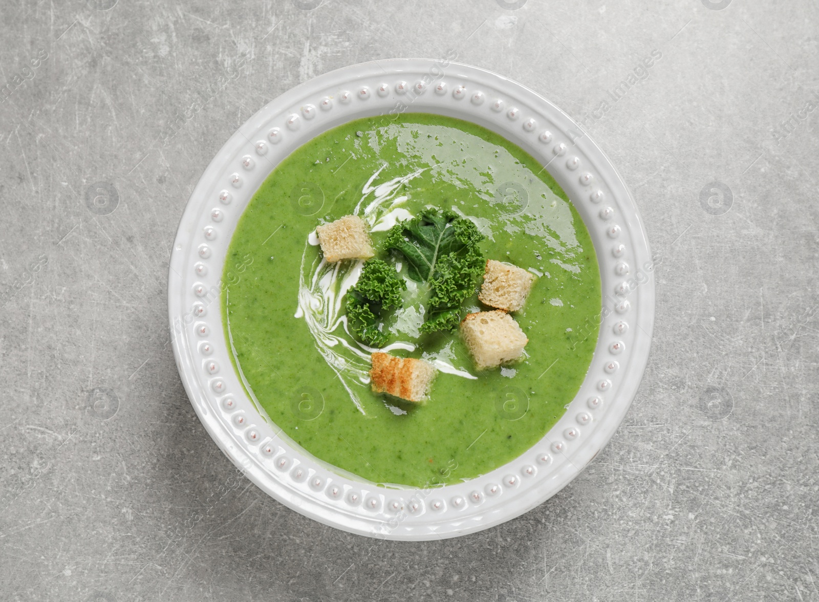 Photo of Tasty kale soup with croutons on grey table, top view