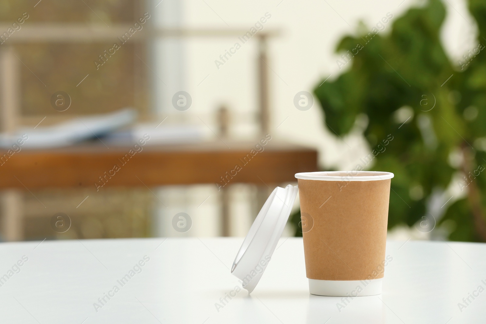 Photo of Cardboard cup of coffee on table indoors. Space for text