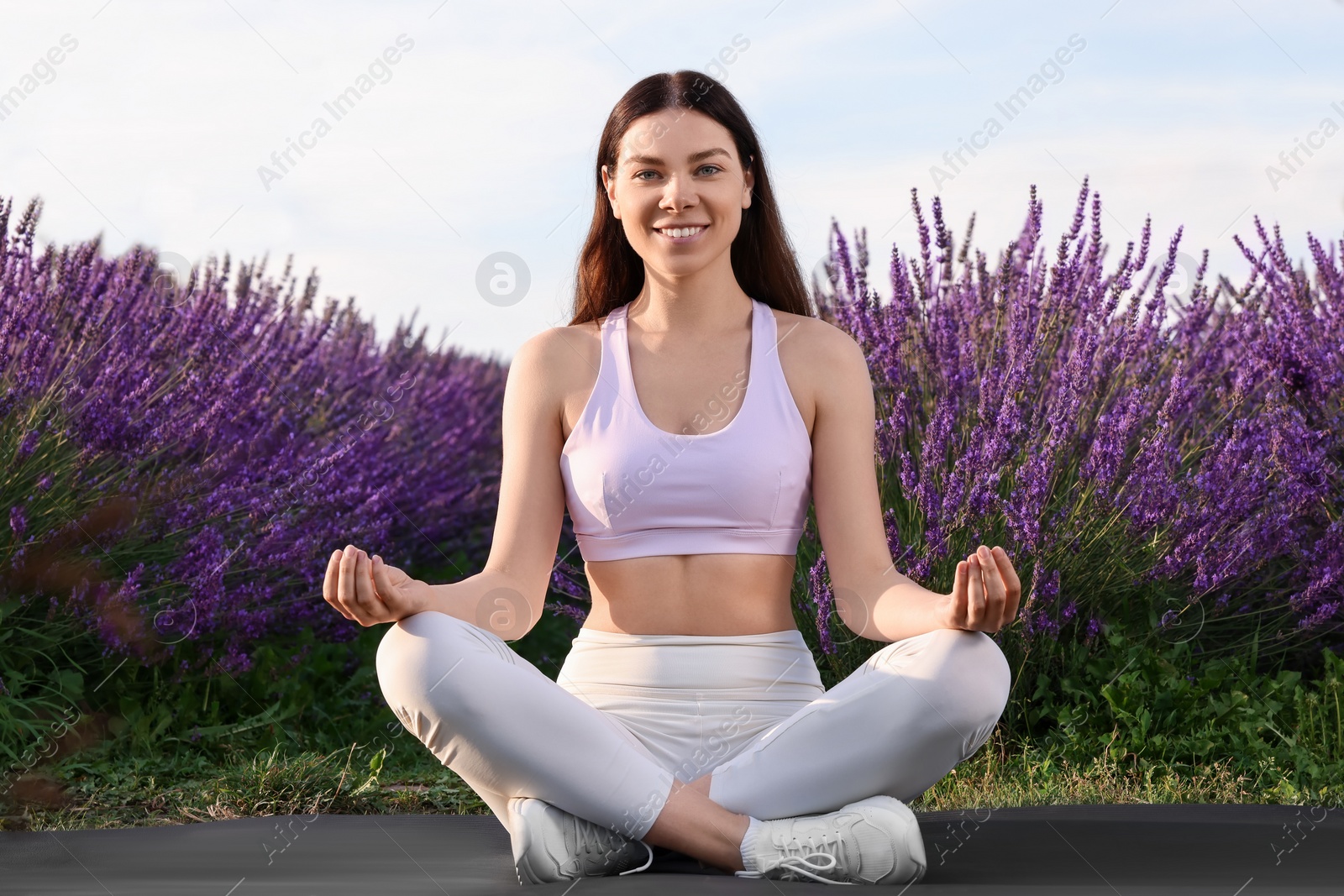 Photo of Smiling woman practicing yoga near lavender outdoors