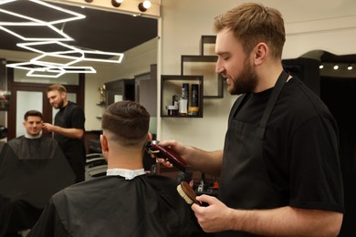 Photo of Professional hairdresser making stylish haircut in salon