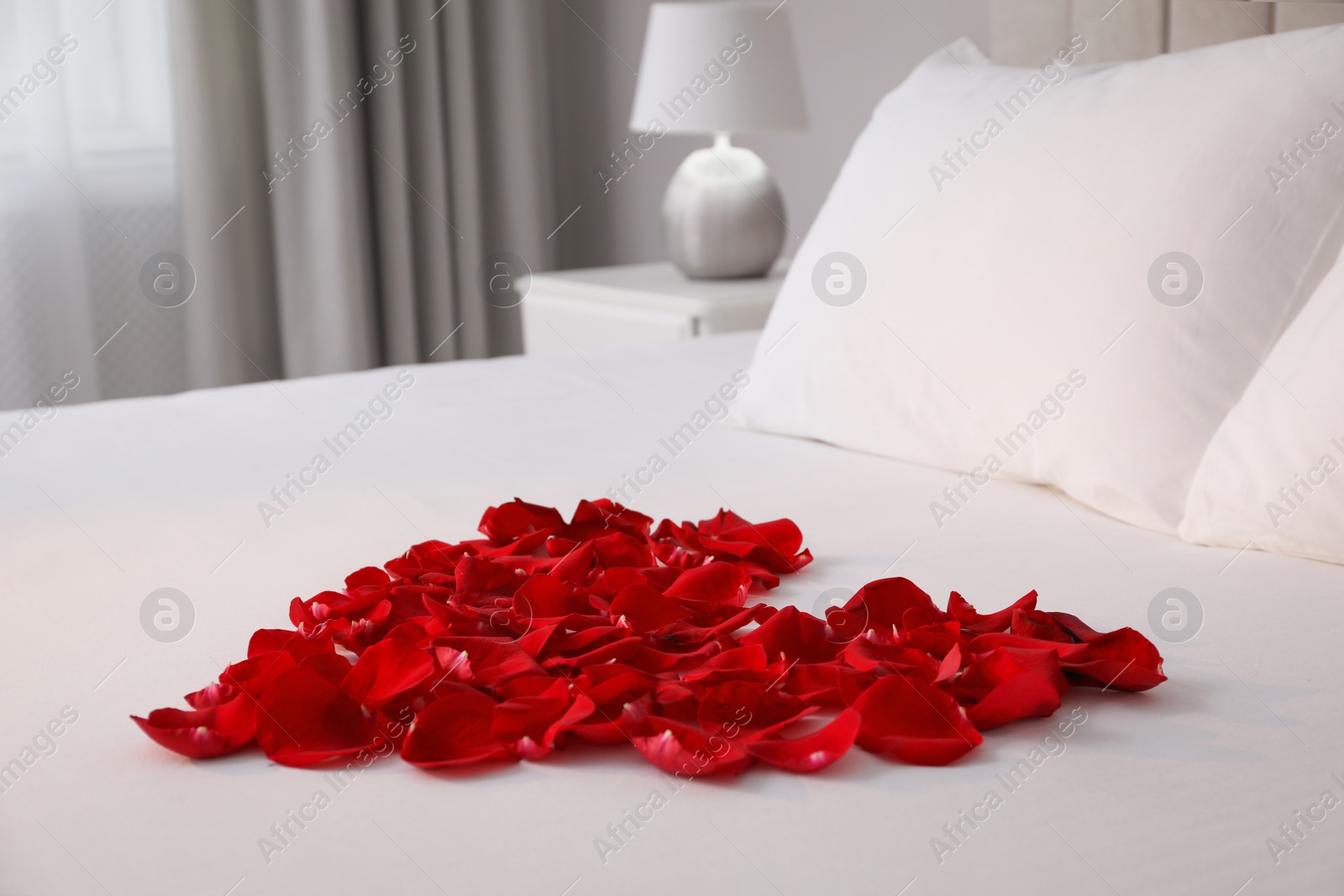 Beautiful heart of red rose petals on bed in room Photo of Beautiful heart of red rose petals on bed in room