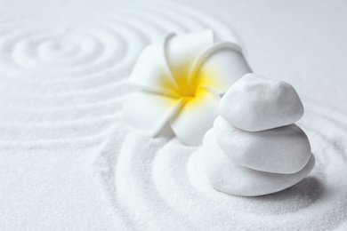 Photo of Stack of white stones and beautiful flower on sand with pattern. Zen, meditation, harmony