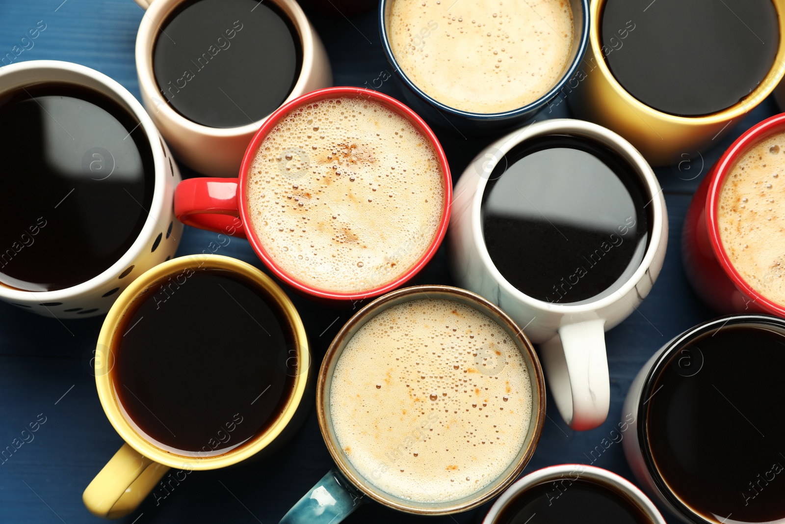 Photo of Many cups of different coffee drinks on blue table, flat lay