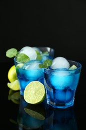 Photo of Delicious cocktails with ice balls, mint and lime on black background