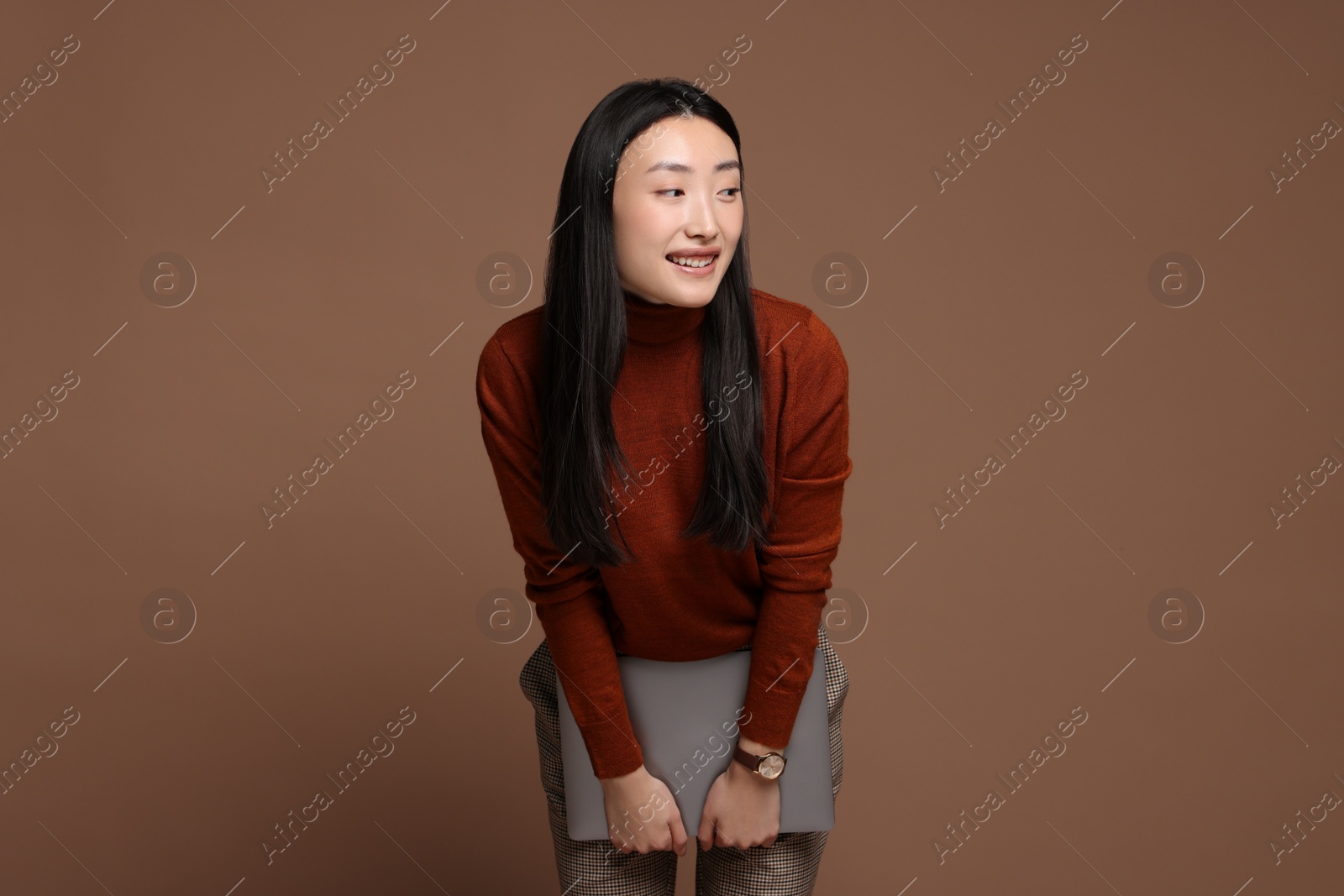 Photo of Portrait of smiling woman with laptop on brown background