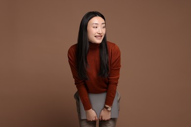 Photo of Portrait of smiling woman with laptop on brown background