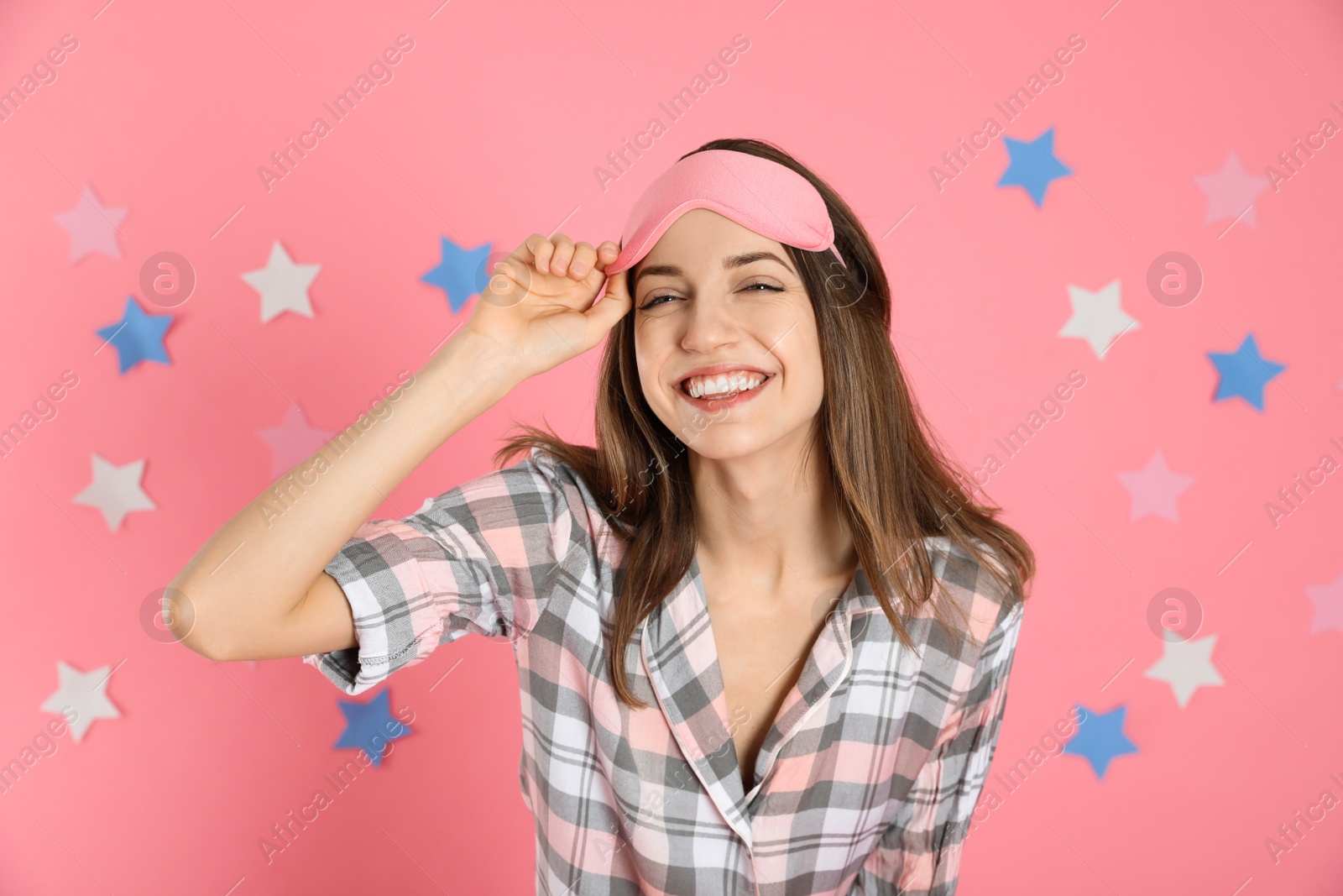 Photo of Beautiful woman wearing pajamas and sleep mask on pink background. Bedtime