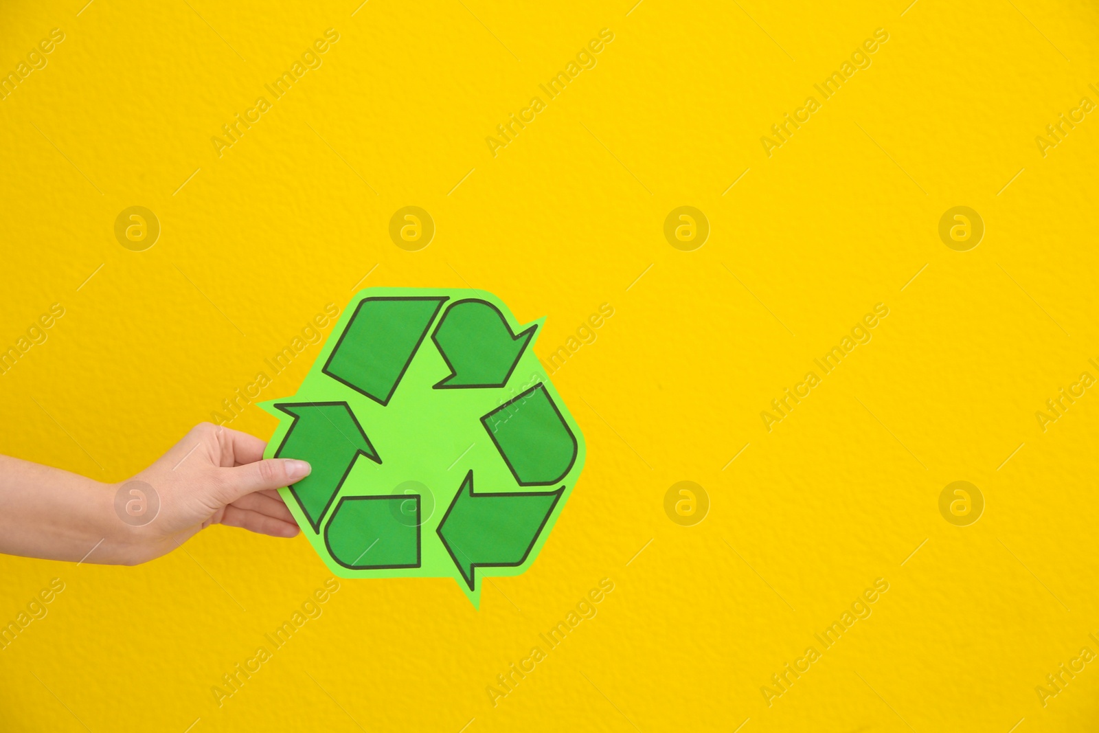 Photo of Woman holding recycling symbol on color background, closeup. Space for text