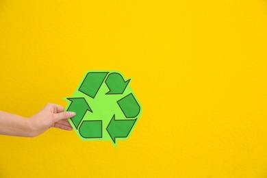 Woman holding recycling symbol on color background, closeup. Space for text