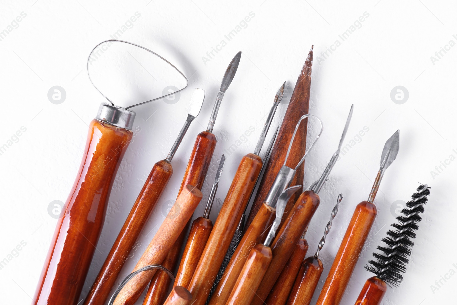 Photo of Set of different clay crafting tools on white textured table, flat lay