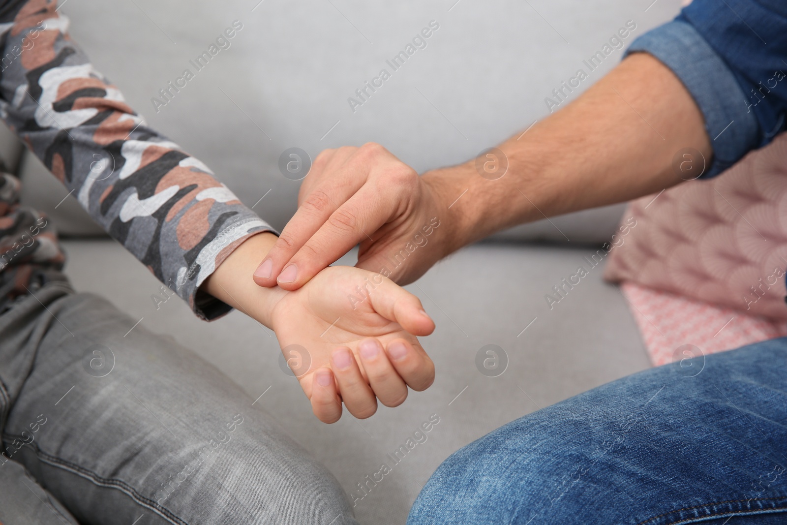 Photo of Man checking little boy's pulse with fingers indoors, closeup
