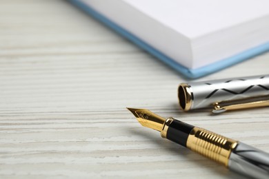 Photo of Beautiful fountain pen with ornate nib on white wooden table, closeup. Space for text