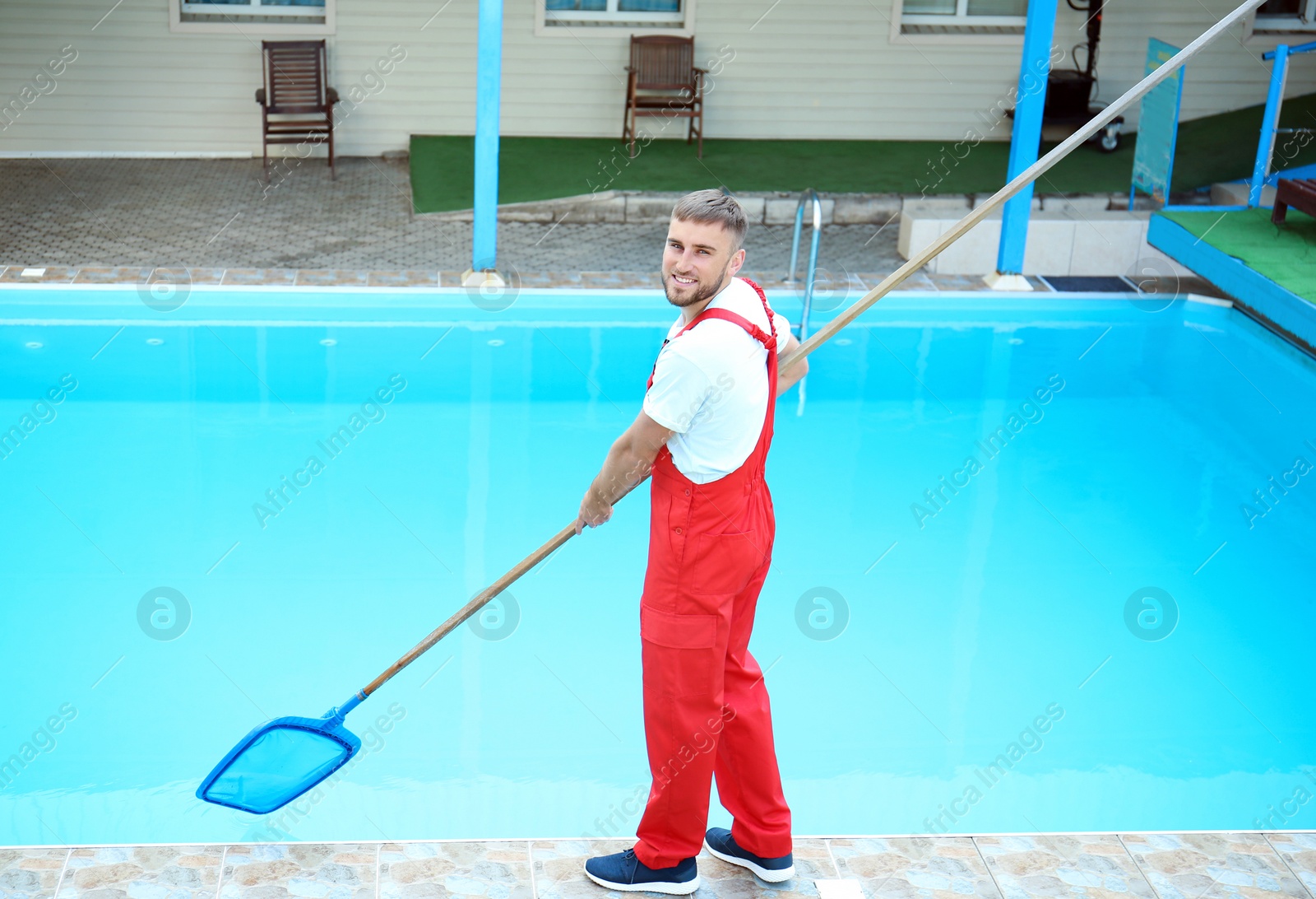 Photo of Male worker cleaning outdoor pool with scoop net