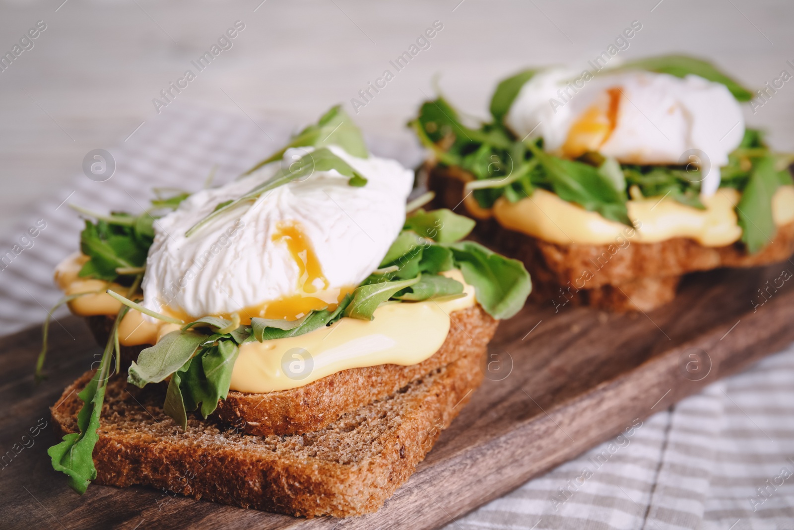Photo of Delicious sandwiches with arugula and egg on wooden board, closeup