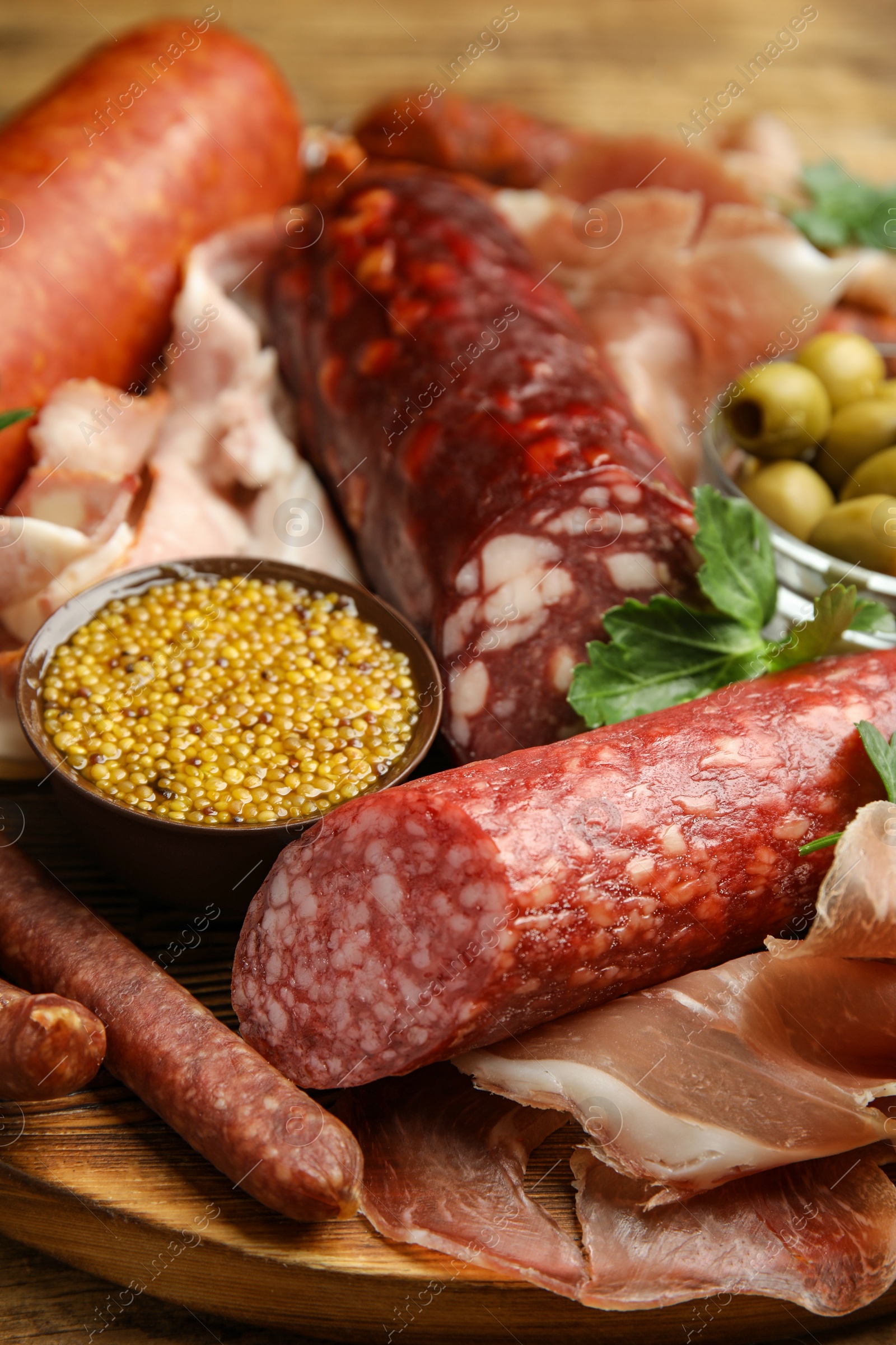 Photo of Different types of sausages served on wooden board, closeup