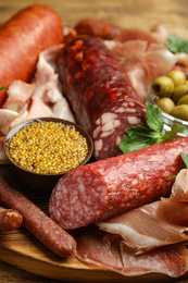 Different types of sausages served on wooden board, closeup