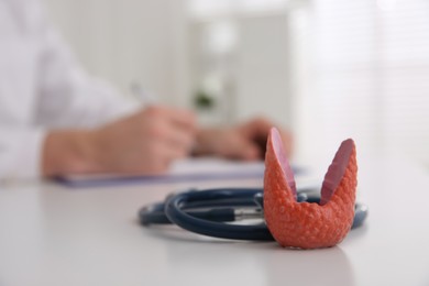 Photo of Thyroid gland model and stethoscope on table indoors. Space for text