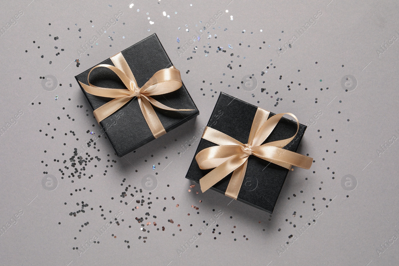 Photo of Beautiful gift boxes and confetti on grey background, flat lay