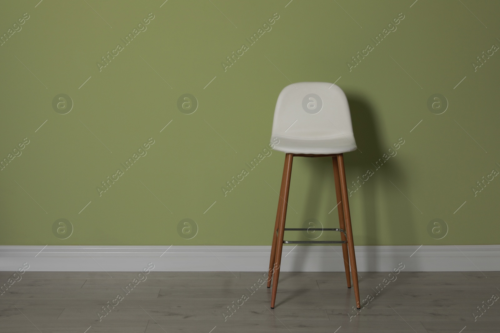 Photo of Stylish bar stool near light green wall indoors. Space for text