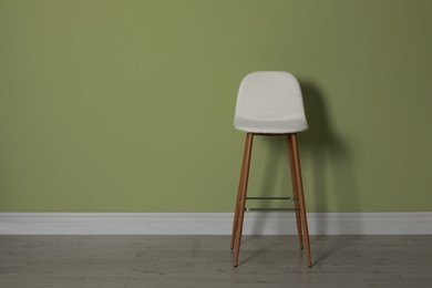 Stylish bar stool near light green wall indoors. Space for text