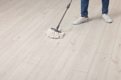Photo of Man cleaning floor with mop indoors, closeup. Space for text
