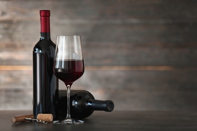 Photo of Composition with glass and bottles of red wine on table. Space for text