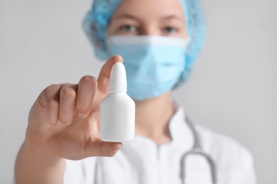 Photo of Doctor holding nasal spray on white background, selective focus