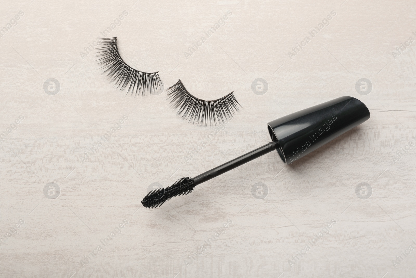 Photo of Mascara brush and artificial eyelashes on light background, top view