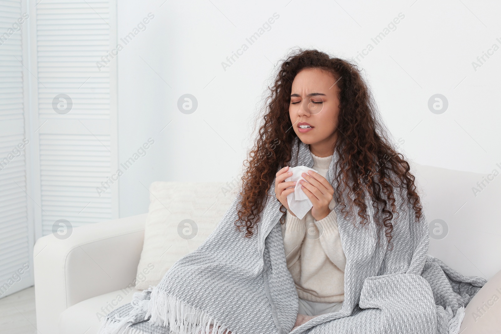 Photo of Sick African American woman sneezing at home, space for text