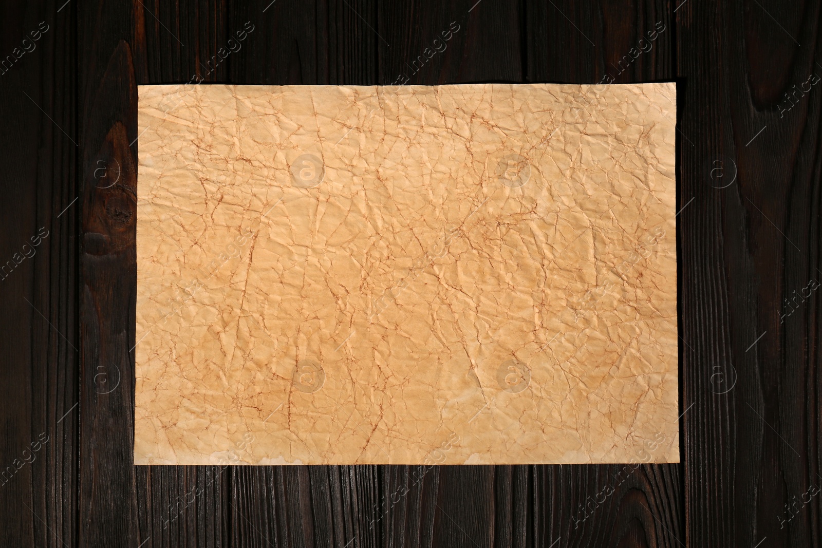 Photo of Sheet of old parchment paper on wooden table, top view