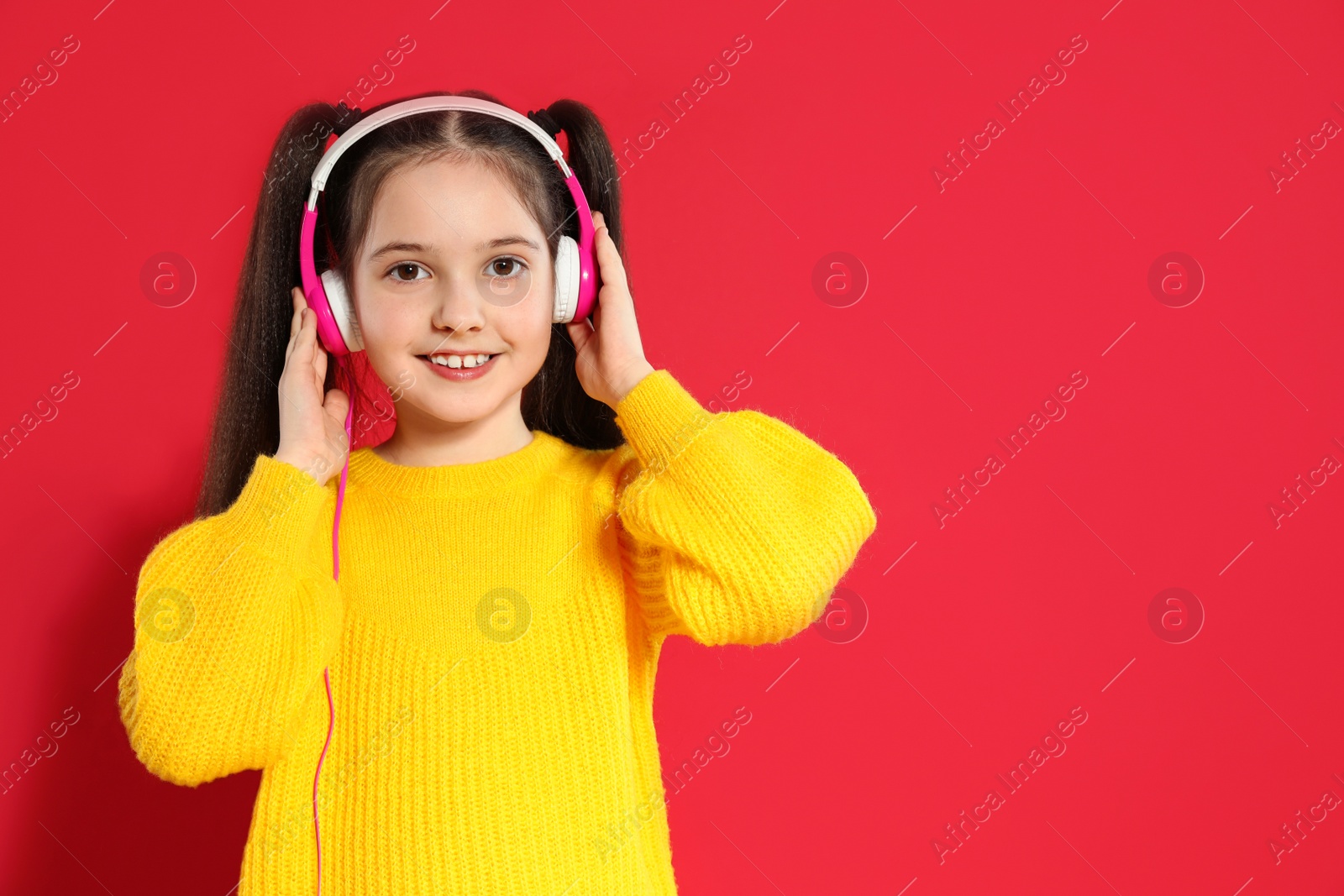 Photo of Cute girl enjoying music in headphones on color background. Space for text