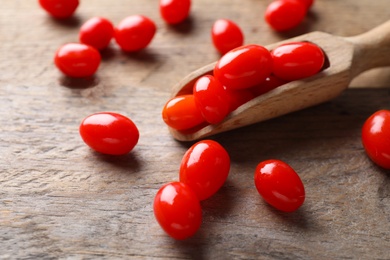 Photo of Fresh ripe goji berries and scoop on wooden table, closeup