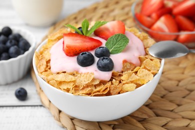 Photo of Delicious crispy cornflakes, yogurt and fresh berries in bowl on white table, closeup. Healthy breakfast