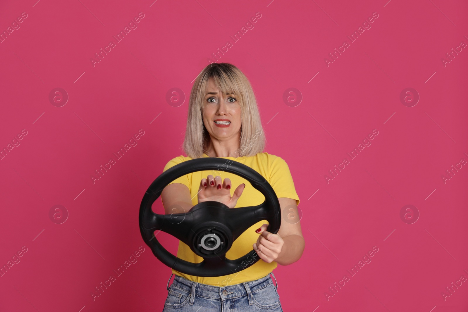 Photo of Emotional woman with steering wheel on crimson background