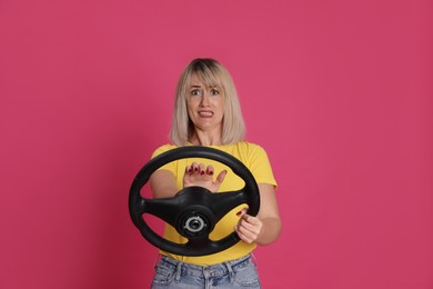 Photo of Emotional woman with steering wheel on crimson background
